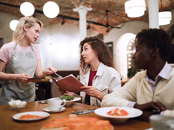 Three people ordering food at a restaurant via waiter